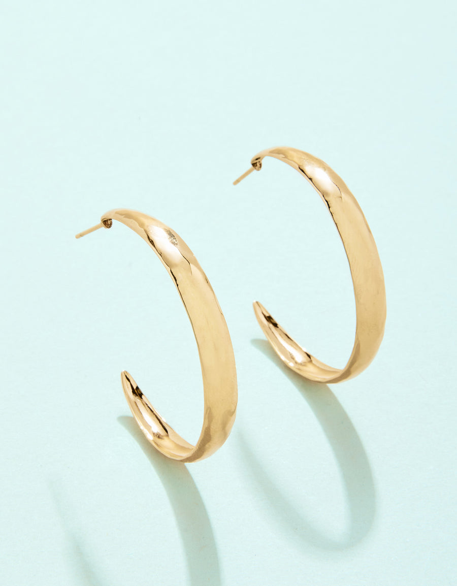 Gold hoop earrings on a light blue background