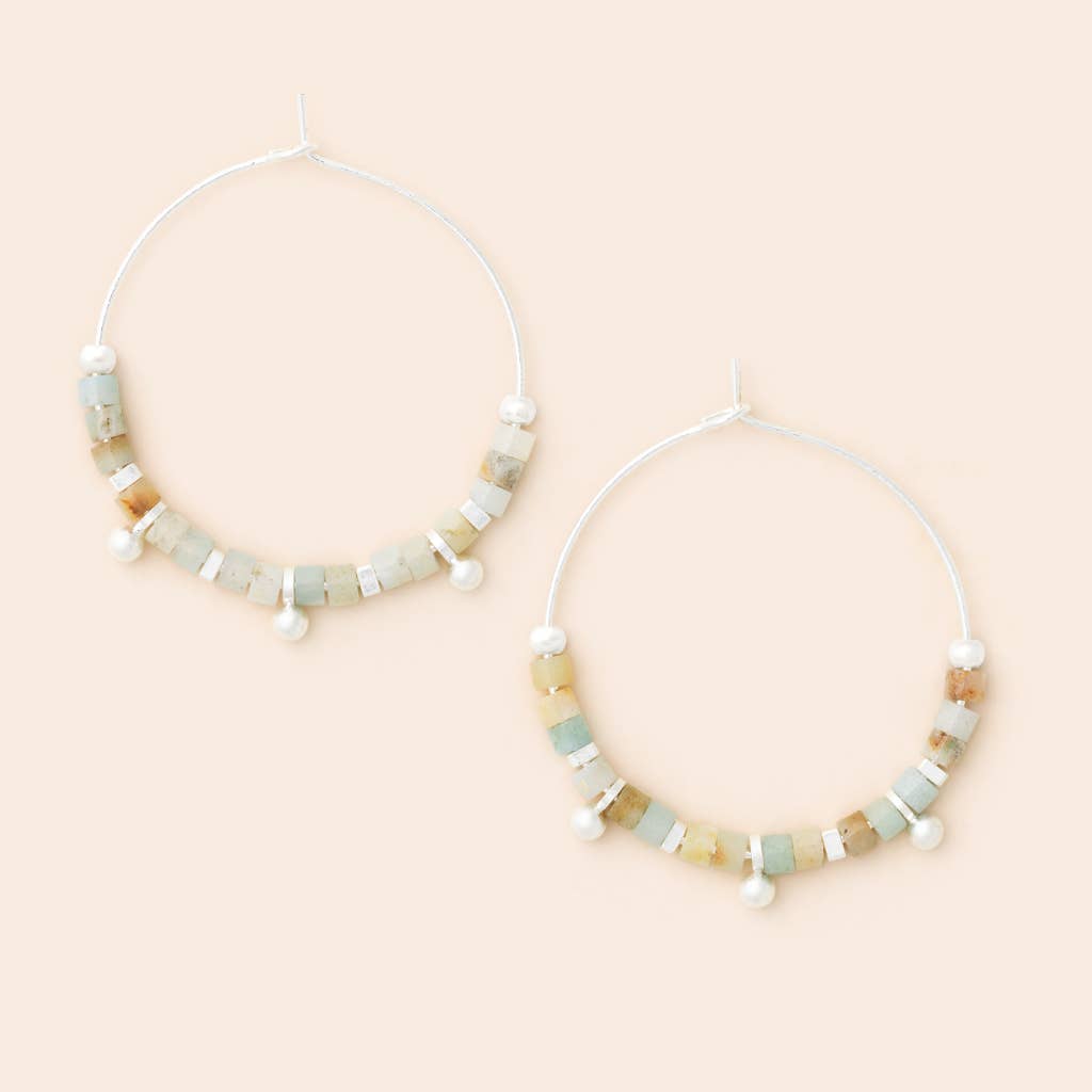 A pair of hoop earrings with small disc-shaped semi-precious gemstones in varying shades of blue and green, attached to a hoop with a silver finish.
