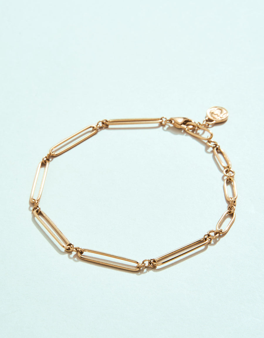 Gold bracelet on a light blue background