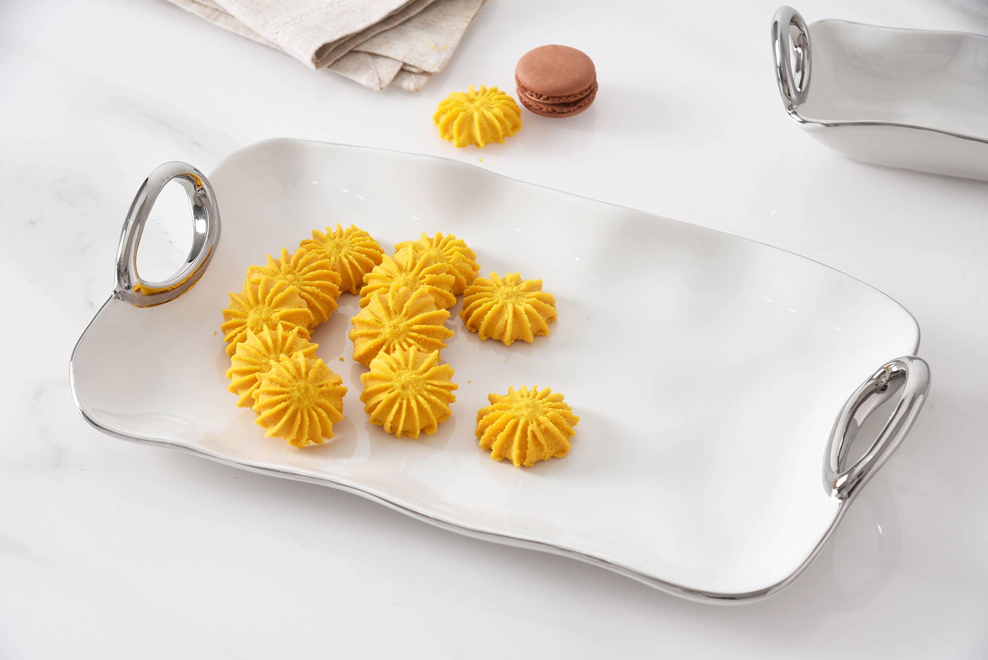 Silver tray with yellow cookies on a white surface