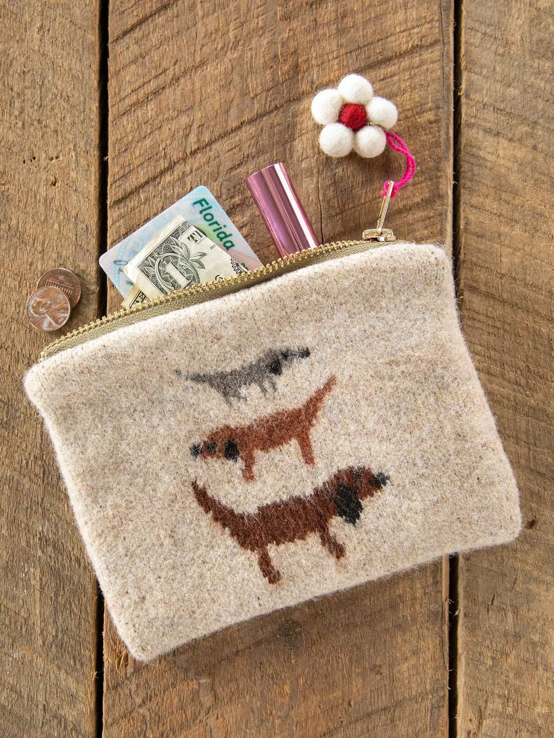 Beige pouch with embroidered dogs on a wooden surface