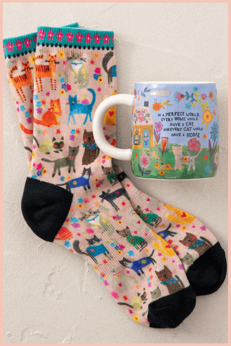 Colorful socks with cat patterns and a matching mug on a light background