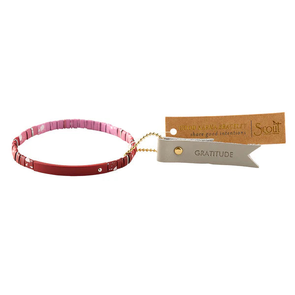 A matte ombre red and pink bracelet with a leather keychain and a hangtag that reads 'Good Karma'.