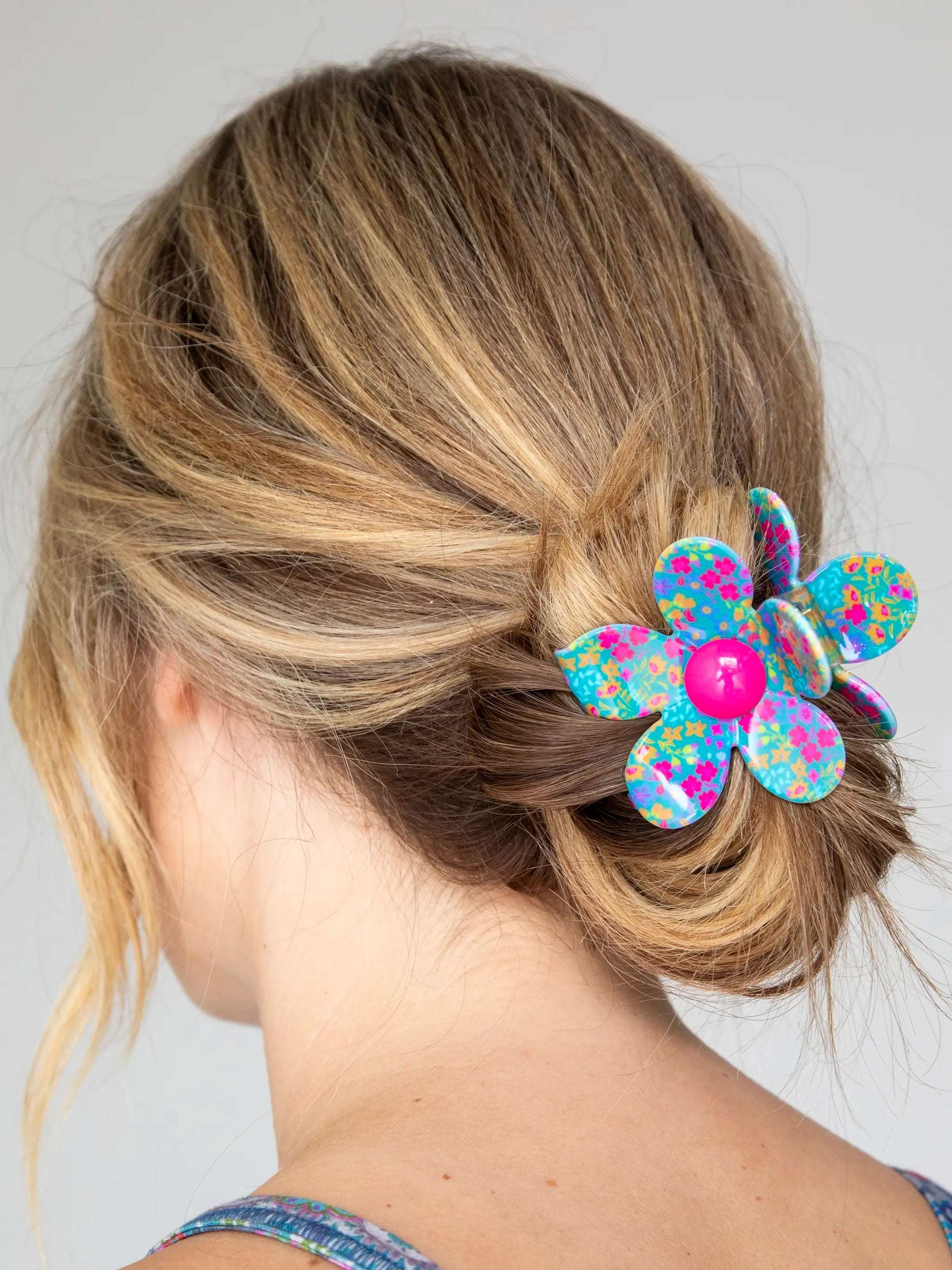 Woman with a colorful flower hair clip in her hair against a plain background
