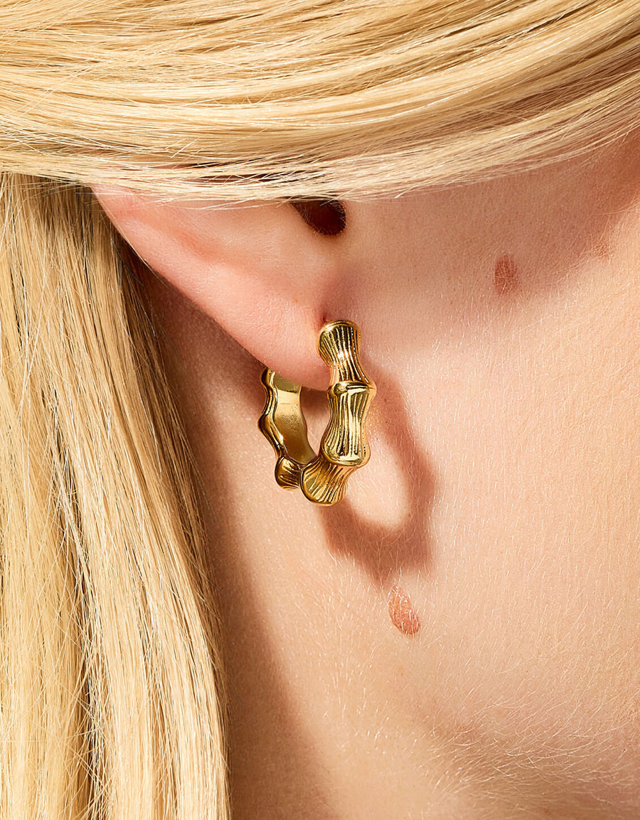 Gold hoop earring worn by a person with blonde hair.