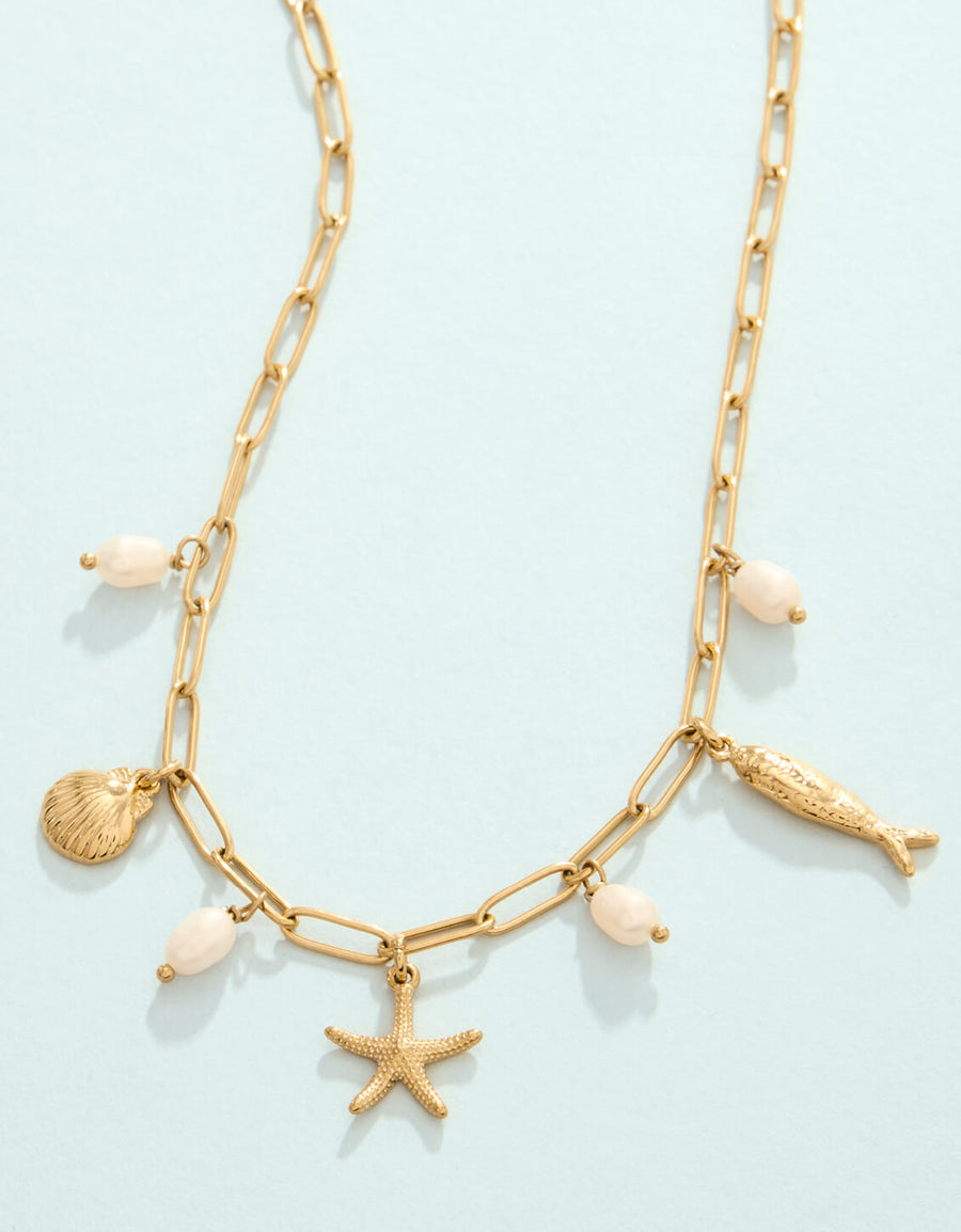 Gold chain necklace with shell and starfish charms on a light blue background