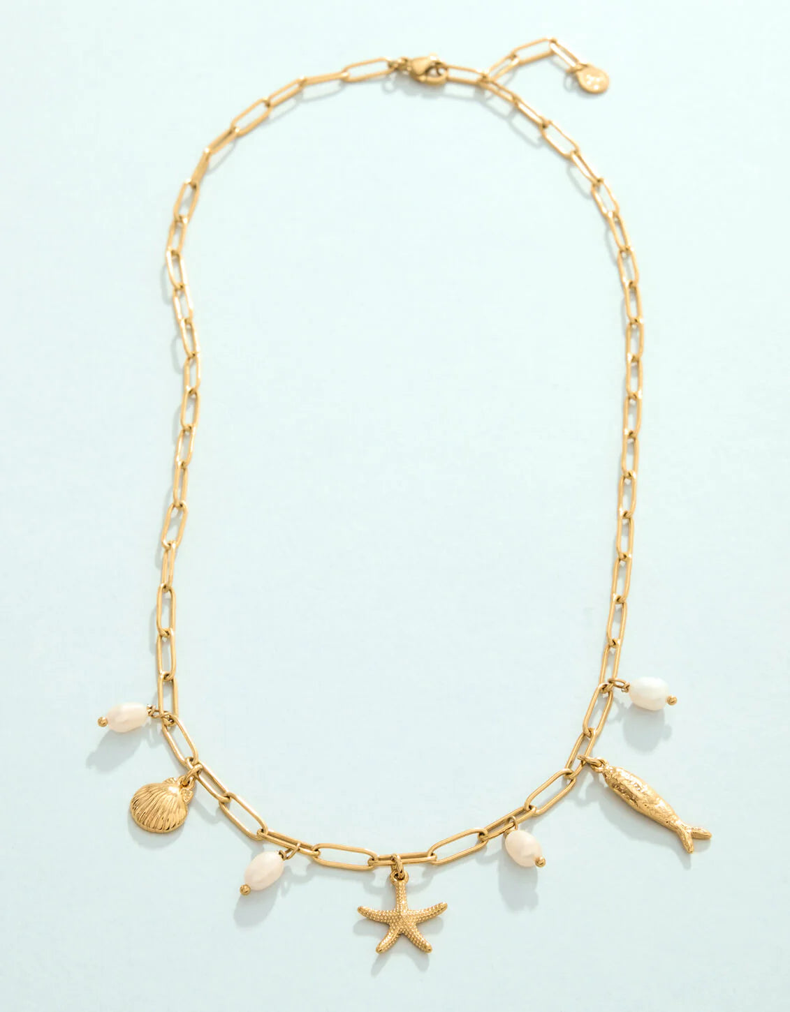 Gold necklace with shell and starfish charms on a light blue background