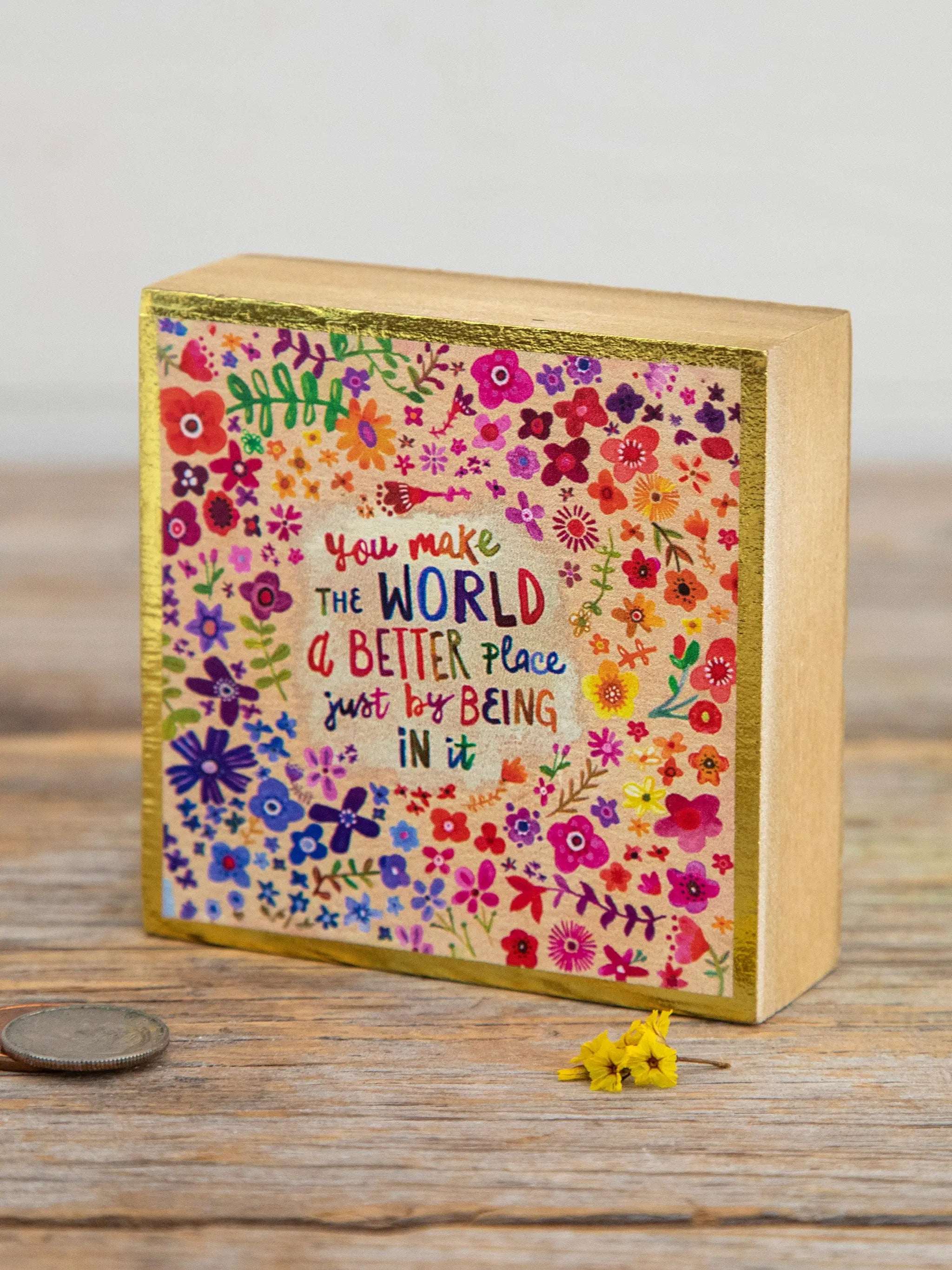 Decorative wooden box with floral design and motivational quote on a wooden surface.