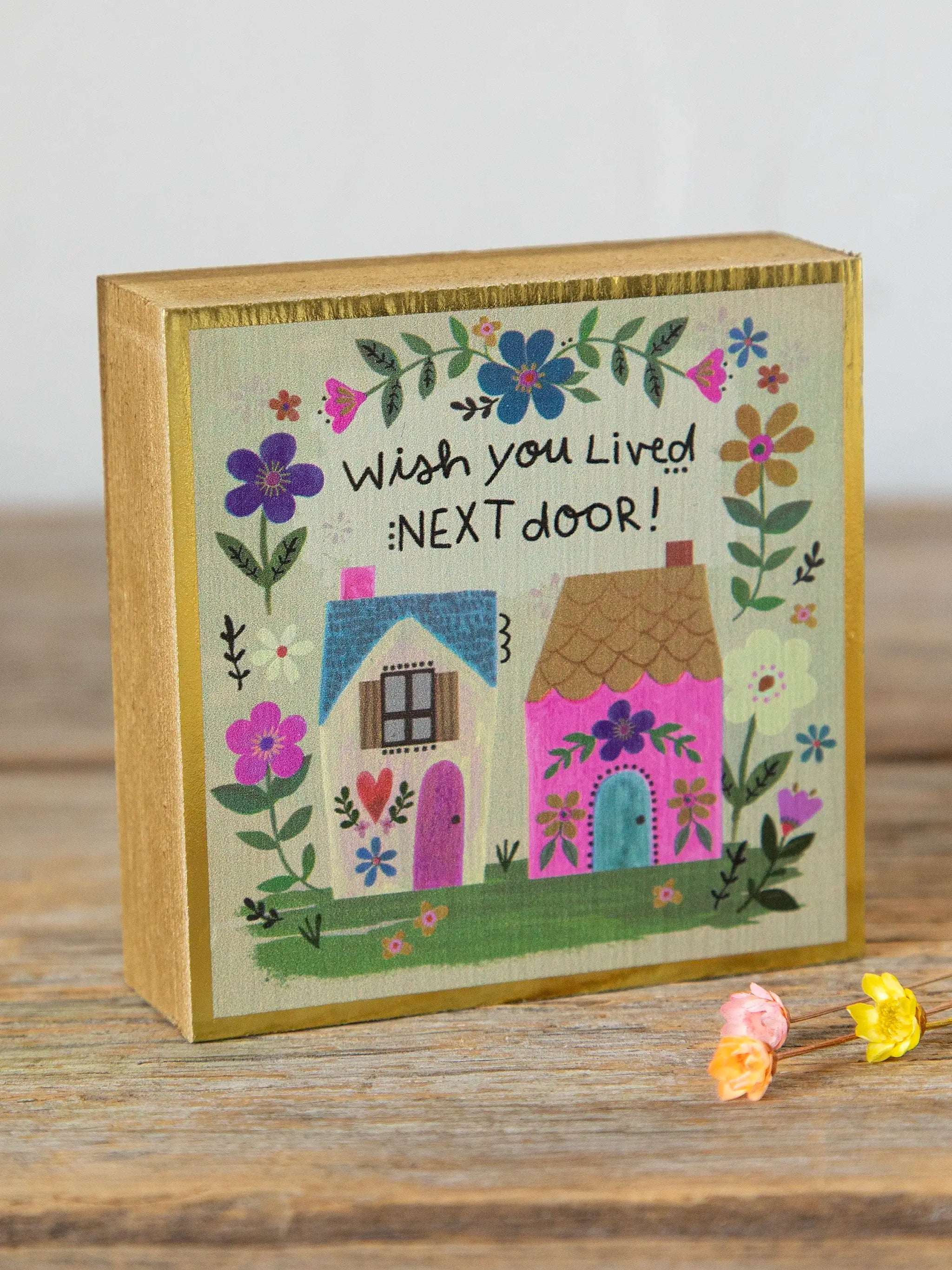 Decorative box with houses and flowers, featuring the text 'Wish you lived next door!'.