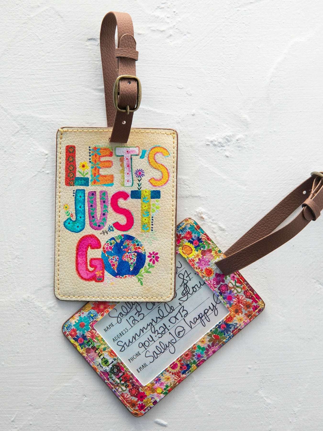 Two luggage tags with colorful text and floral designs on a white background