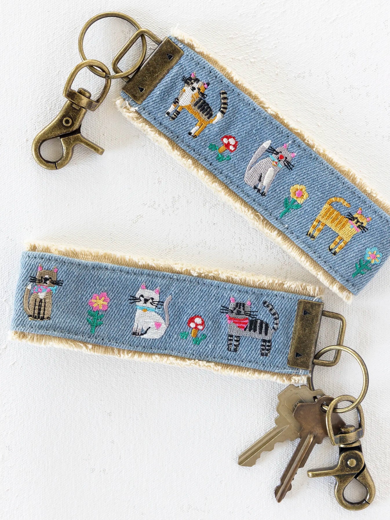 Keychain with embroidered cat designs on a blue fabric background