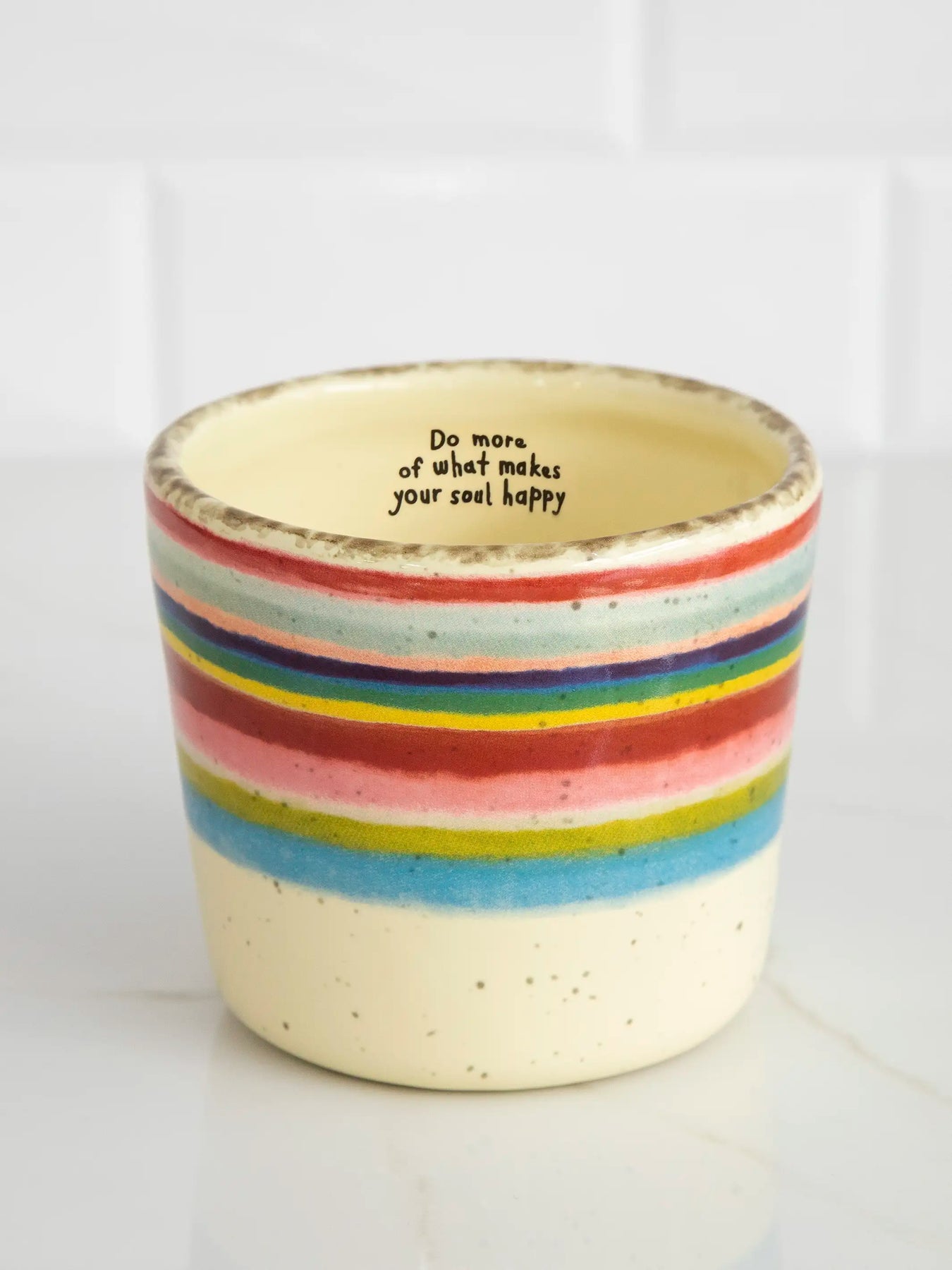 Ceramic cup with rainbow stripes and motivational quote on a white background