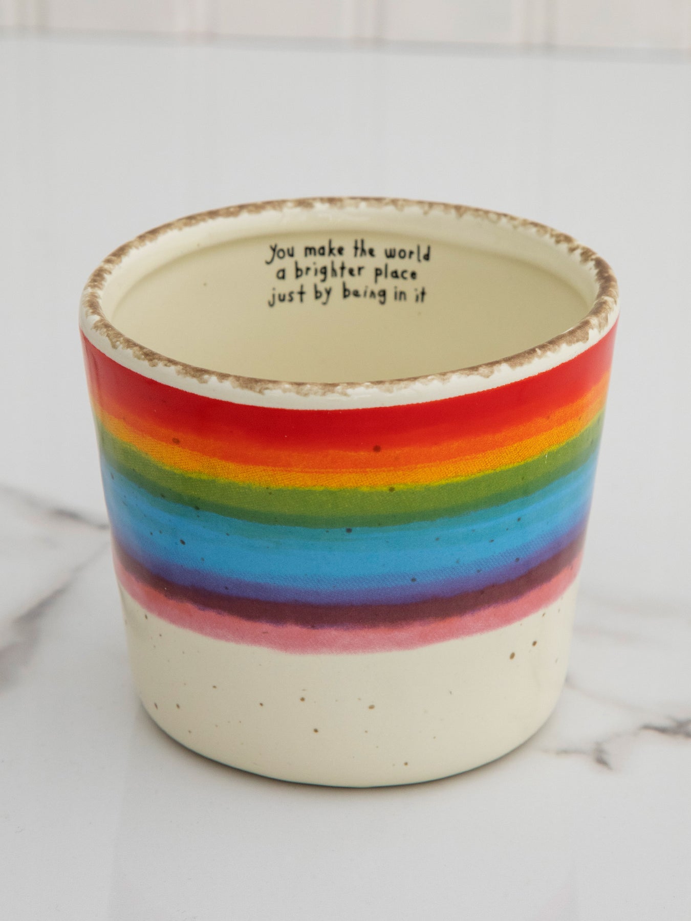 Colorful striped pot with a motivational quote on a white background