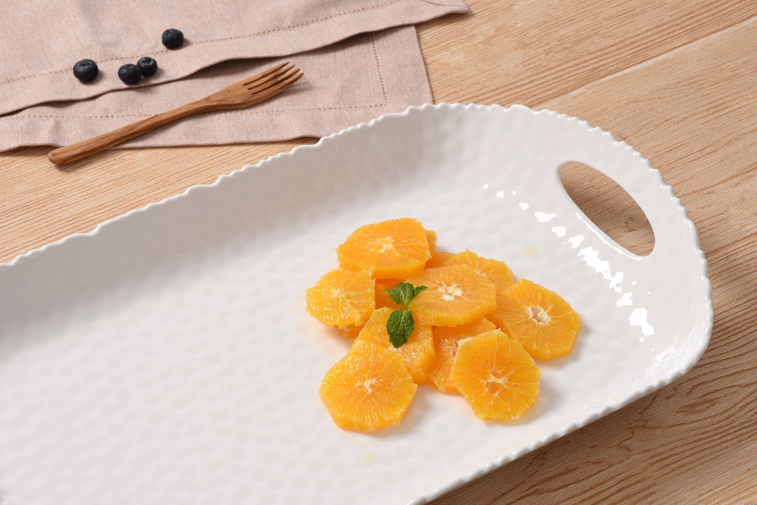 White ceramic platter with sliced oranges on a wooden surface