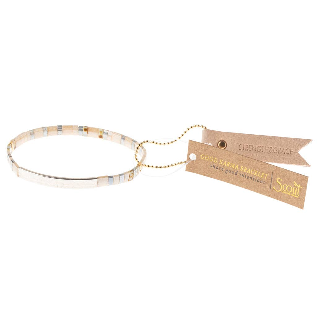 A Miyuki bracelet with a combination of matte and pearlescent beads, featuring a 14K gold dipped bar with an engraved good intention, and a leather keychain hangtag.