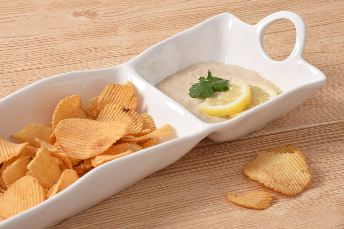 White ceramic dish with potato chips and a dip on a wooden surface