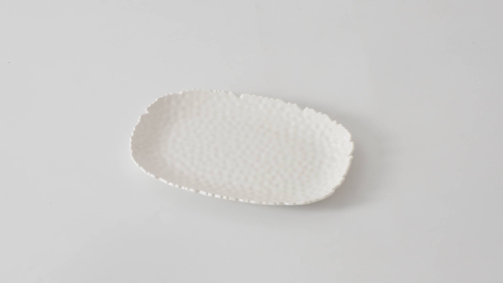 White ceramic plate with textured surface on a light gray background