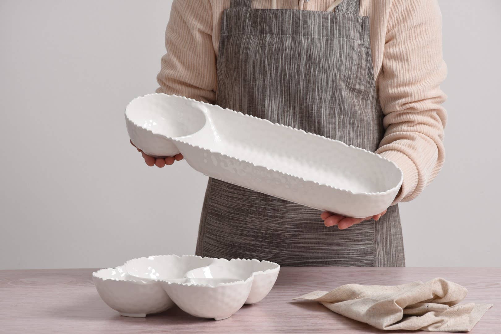 Person holding a white ceramic tray with a plain background