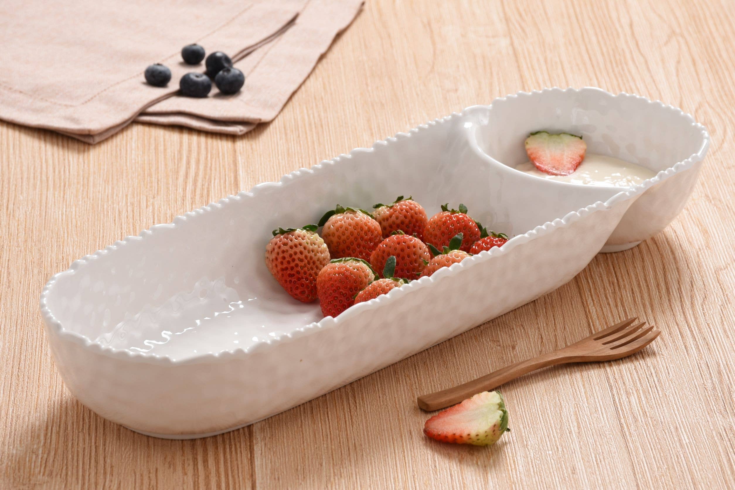White ceramic dish with strawberries and blueberries on a wooden surface