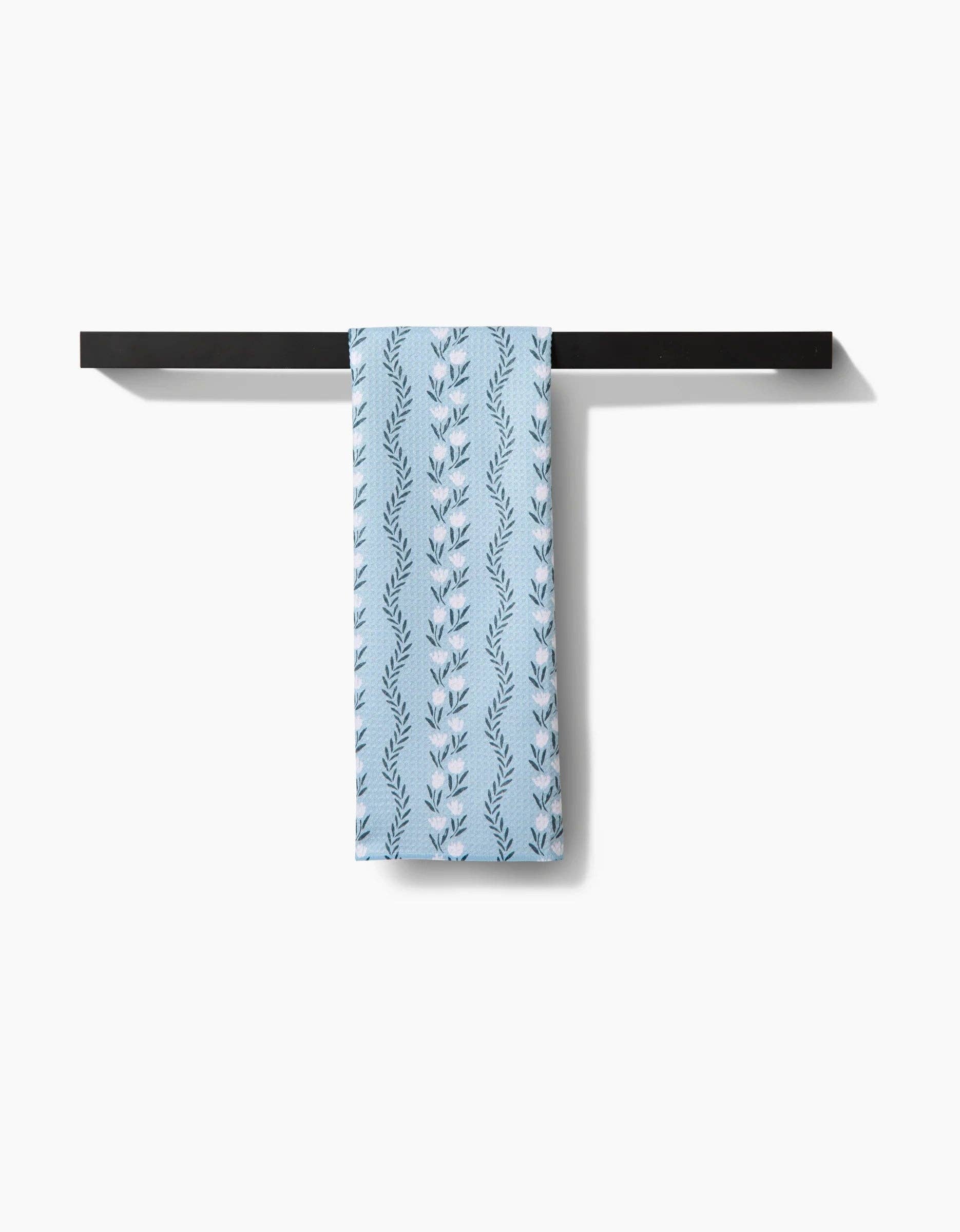 Blue patterned towel hanging on a black towel rack against a white background