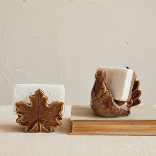 Two ceramic items resembling a bird and a leaf on a beige background
