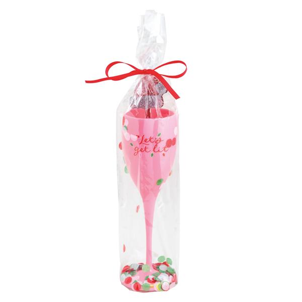 A pink champagne flute gift set wrapped in clear cellophane with a red ribbon bow. The glass features the words 'cheers to you' in script with small red hearts, and colorful confetti is visible at the base.