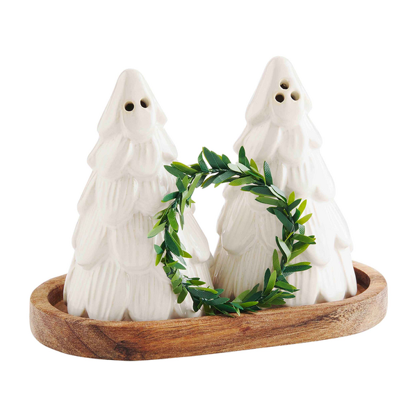 Two white christmas tree-shaped salt and pepper shakers with a green wreath on a wooden base against a white background.